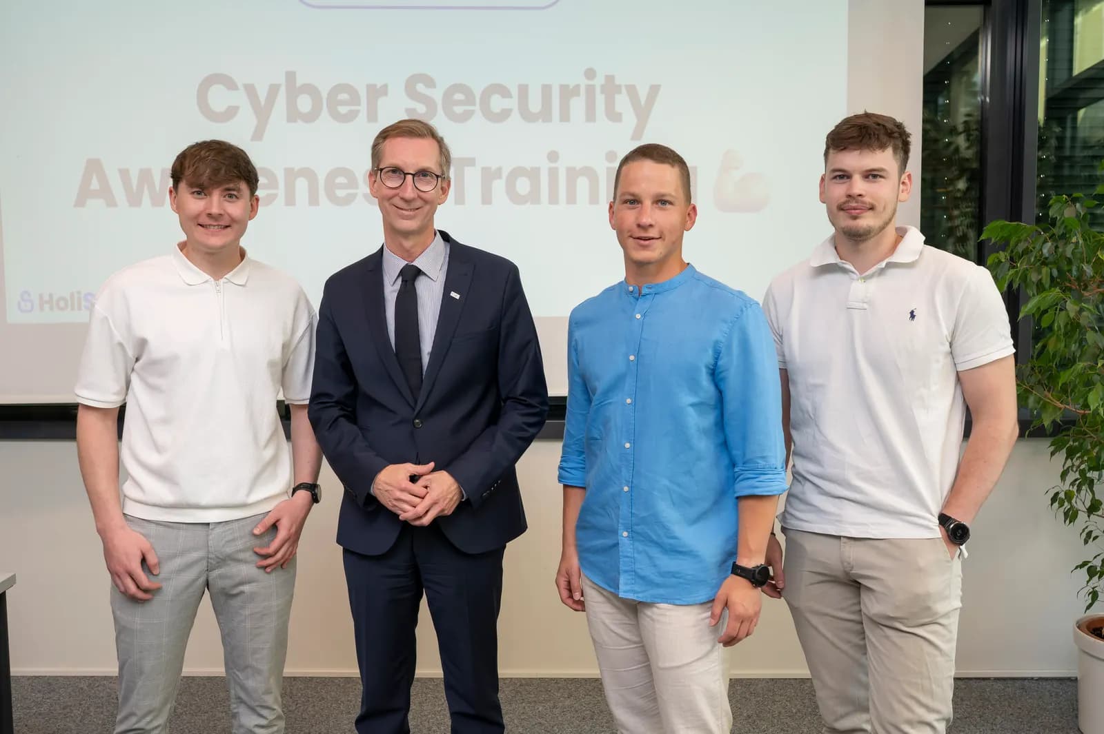 Die HoliSec-Gründer gemeinsam mit dem Gastgeber vor der Titelfolie des Cyber Security Awareness Trainings der KSW